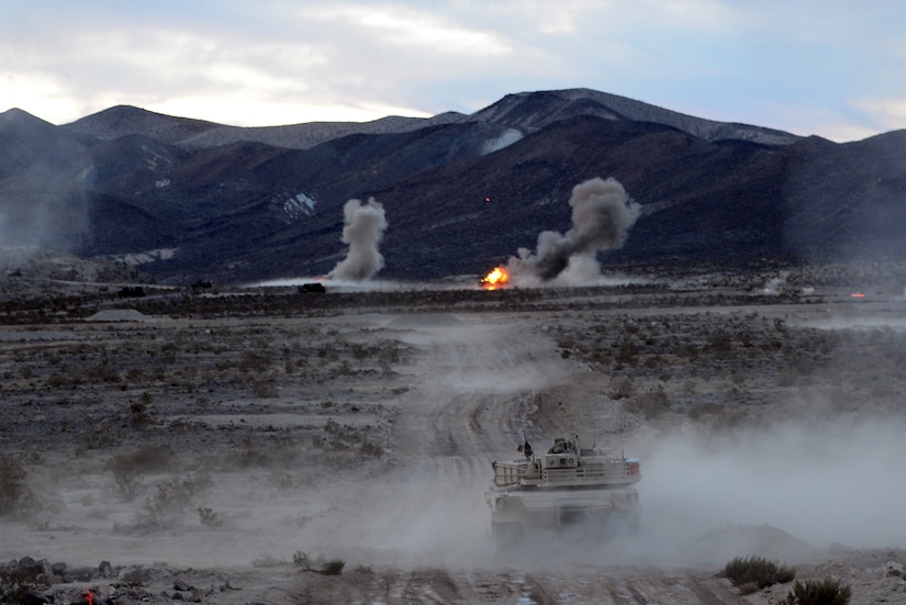 A tank rolls along in a dusty environment. Smoke surrounds it.