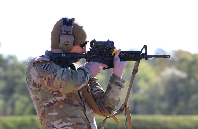 Man in U.S. Army uniform firing rifle on outdoor rifle range.