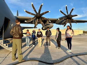 a group of people stand inside a hangar