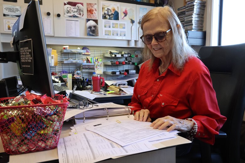 Lady sitting at desk reading papers.