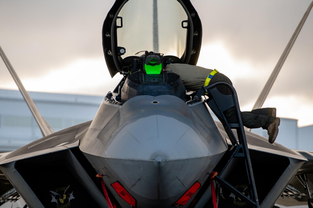 An airman leans into the cockpit of a military aircraft.