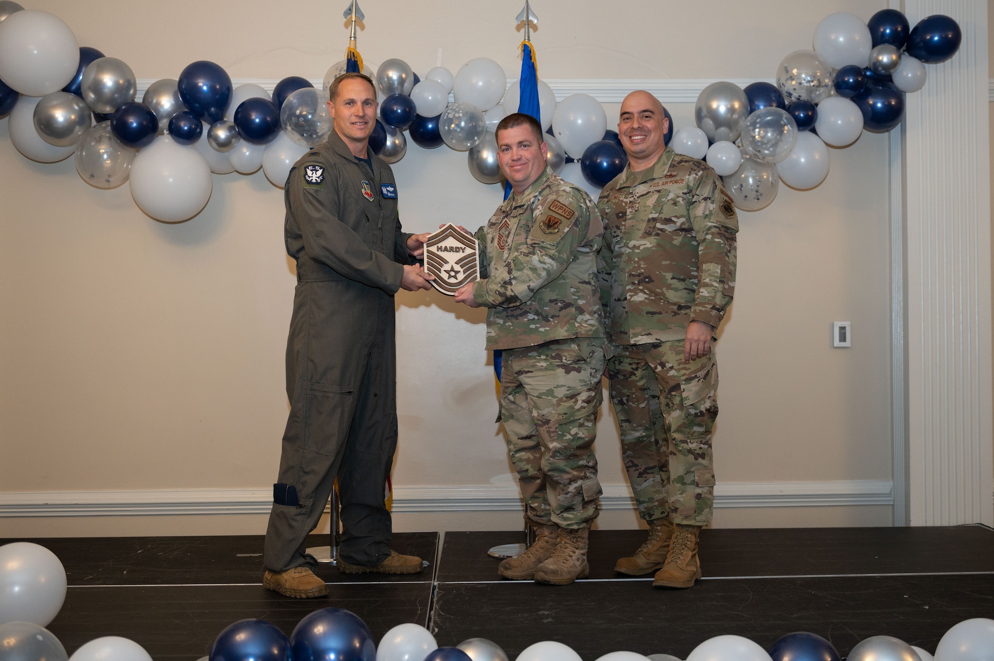 Col. Lucas Teel, 4th Fighter Wing commander, and Chief Master Sgt. Peter Martinez, 4th FW command chief, present a plaque to Senior Master Sgt. select Benjamin Hardy, 333rd Fighter Squadron weapons section chief, during the senior master sergeant release ceremony at Seymour Johnson Air Force Base, North Carolina, March 17, 2023. Air Force officials selected 1,629 master sergeants for promotion to senior master sergeant, out of 16,031 eligible, for a selection rate of 10 percent this promotion cycle. (U.S. Air Force photo by Airman 1st Class Rebecca Sirimarco-Lang)