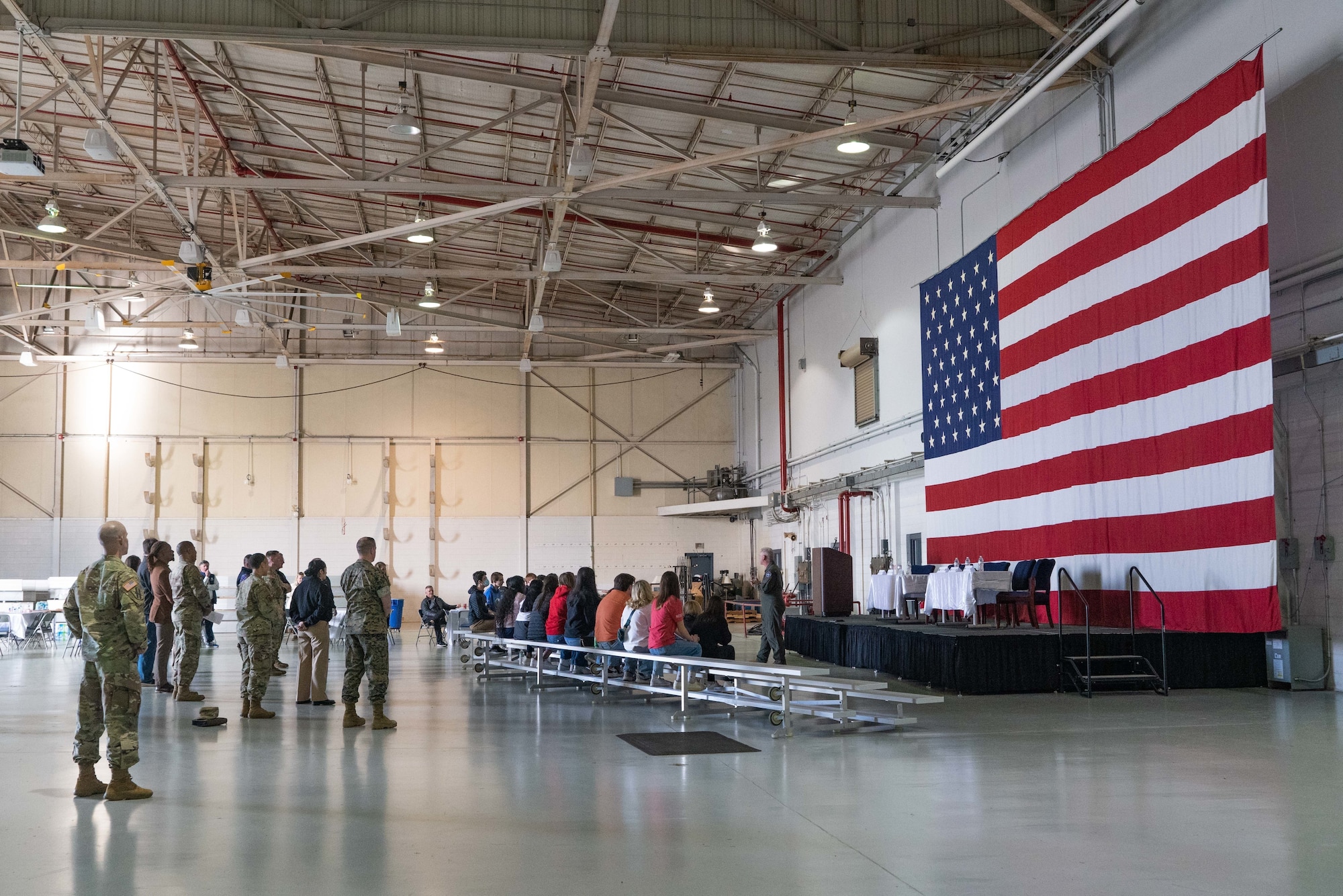 a group of people stand inside a hangar