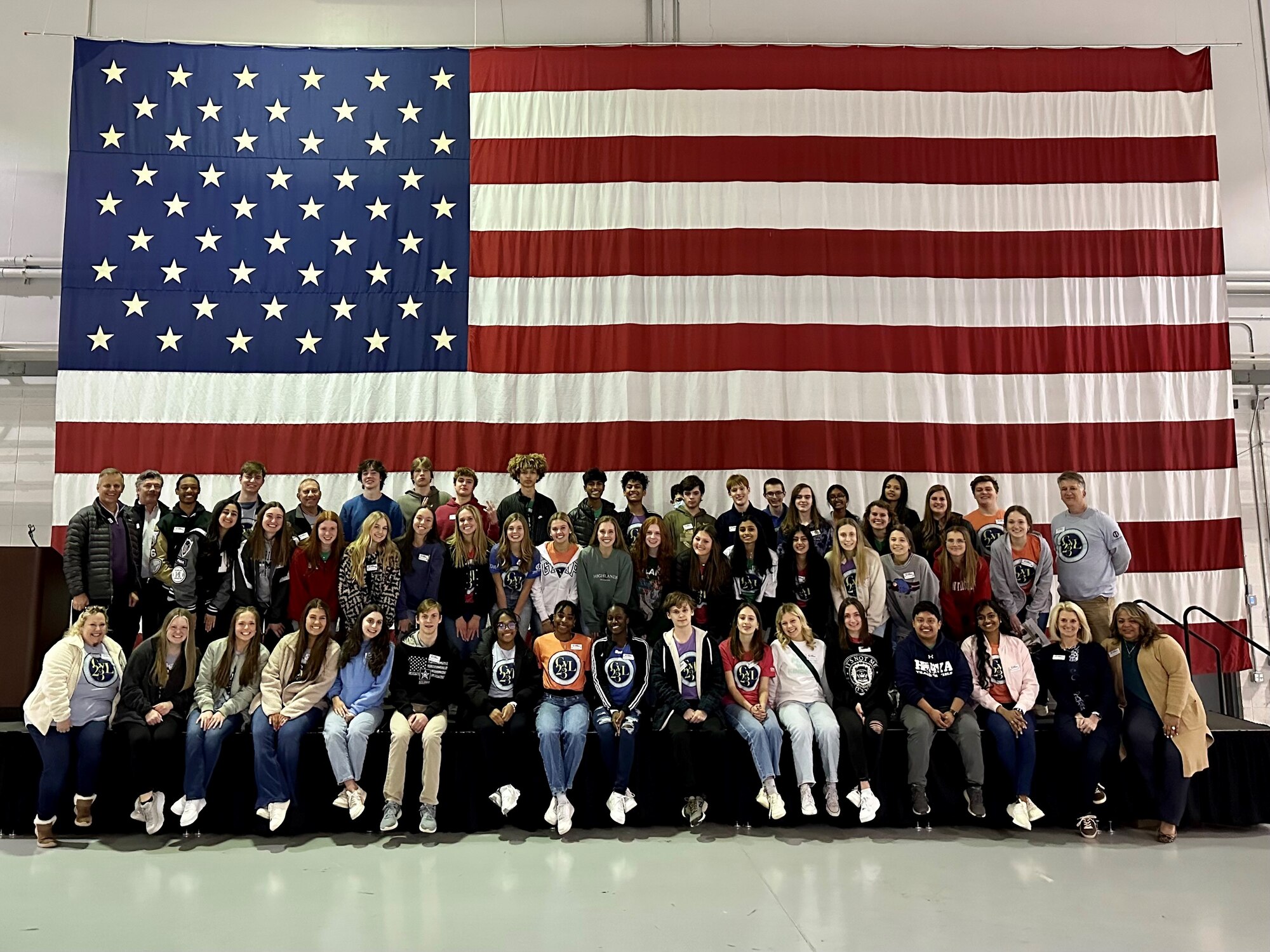 a group of people pose for a photo in front of a flag