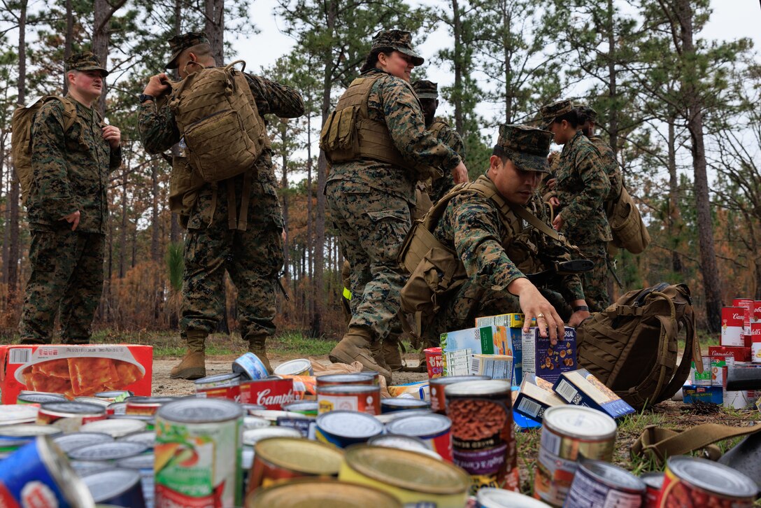 U.S. Marines with 2nd Supply Battalion, 2nd Marine Logistics Group, drop off canned goods at the halfway point of their charity hike on Camp Lejeune, North Carolina, March 10, 2023. Marines with 2nd Supply Battalion hiked a total of six miles carrying and later donating hundreds of canned goods to a local charity in Jacksonville, North Carolina. (U.S. Marine Corps photo by Lance Cpl. Mary Kohlmann)