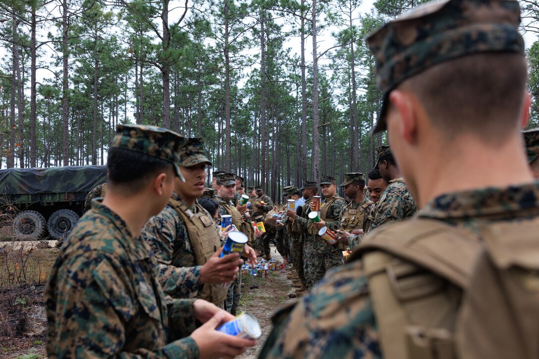 U.S. Marines with 2nd Supply Battalion, 2nd Marine Logistics Group, pass canned goods down a line on Camp Lejeune, North Carolina, March 10, 2023. Marines with 2nd Supply Battalion hiked a total of six miles carrying and later donating hundreds of canned goods to a local charity in Jacksonville, North Carolina. (U.S. Marine Corps photo by Lance Cpl. Mary Kohlmann)