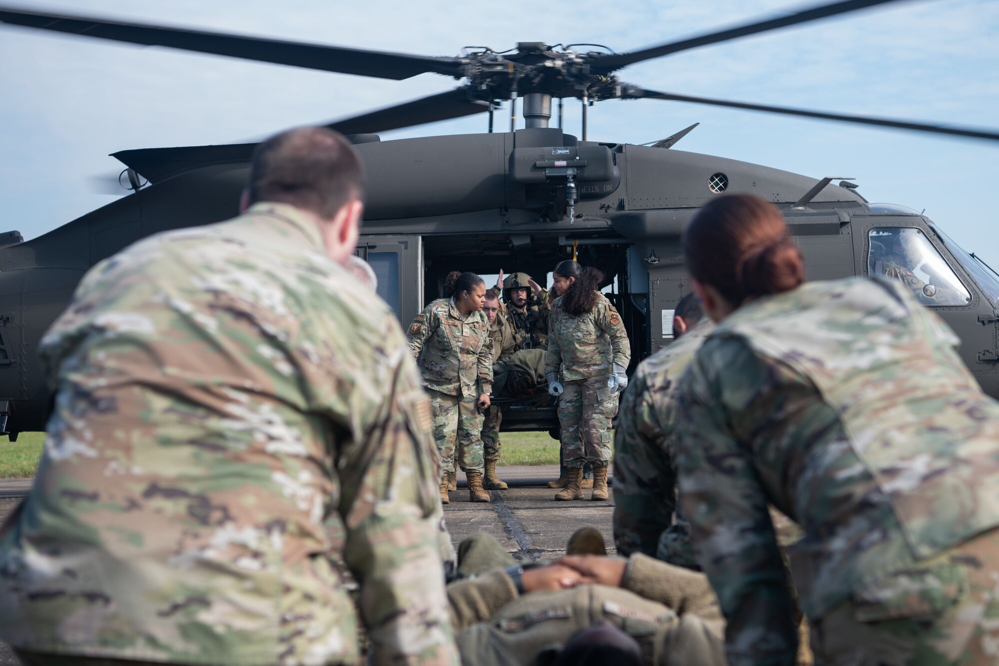 Airmen escort a person onto a helicopter at Maxwell Air Force Base, March 16, 2023. During the helicopter portion of the training, some of the Army’s non-commissioned officers taught Airmen how to escort a patient onto the helicopter while it was running.