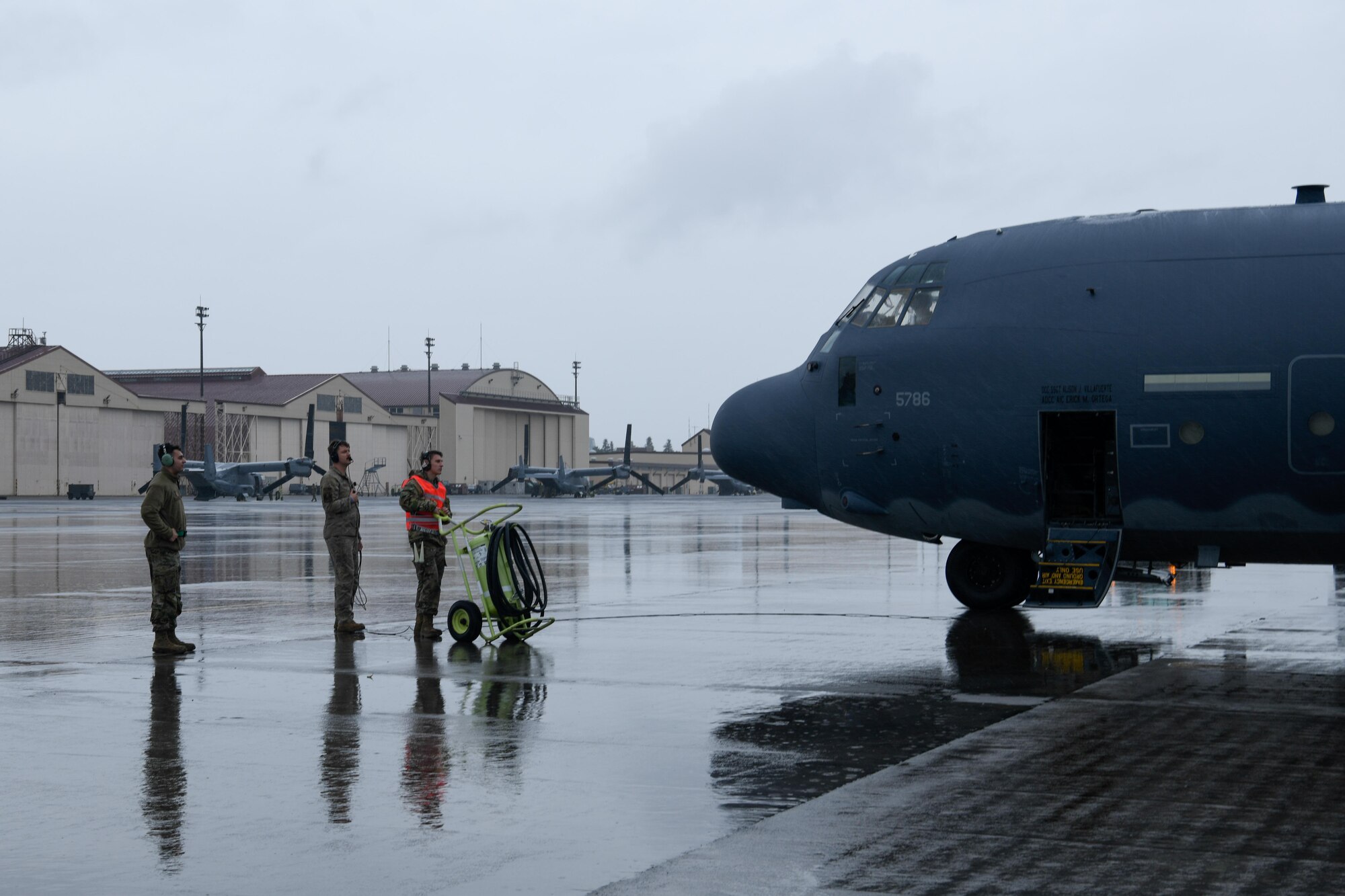 Three people dressed in uniform stand in front of a plane.