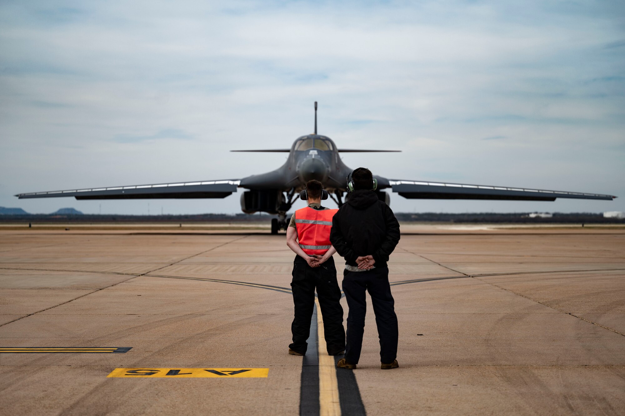 Two 7th Maintenance Group crew chiefs prepare to marshal a B-1B Lancer at Dyess Air Force Base, Texas, March 22, 2023. In preparation for possible inclement weather, Dyess Airmen rapidly prepared over a dozen aircraft to relocate, successfully demonstrating America’s Lift and Strike Base’s ability to achieve dynamic force employment while using agile combat employment. The B-1s were temporarily relocated to Holloman Air Force Base, New Mexico, while the C-130s flew to several airfields throughout the United States. (U.S. Air Force photo by Airman Emma Anderson)