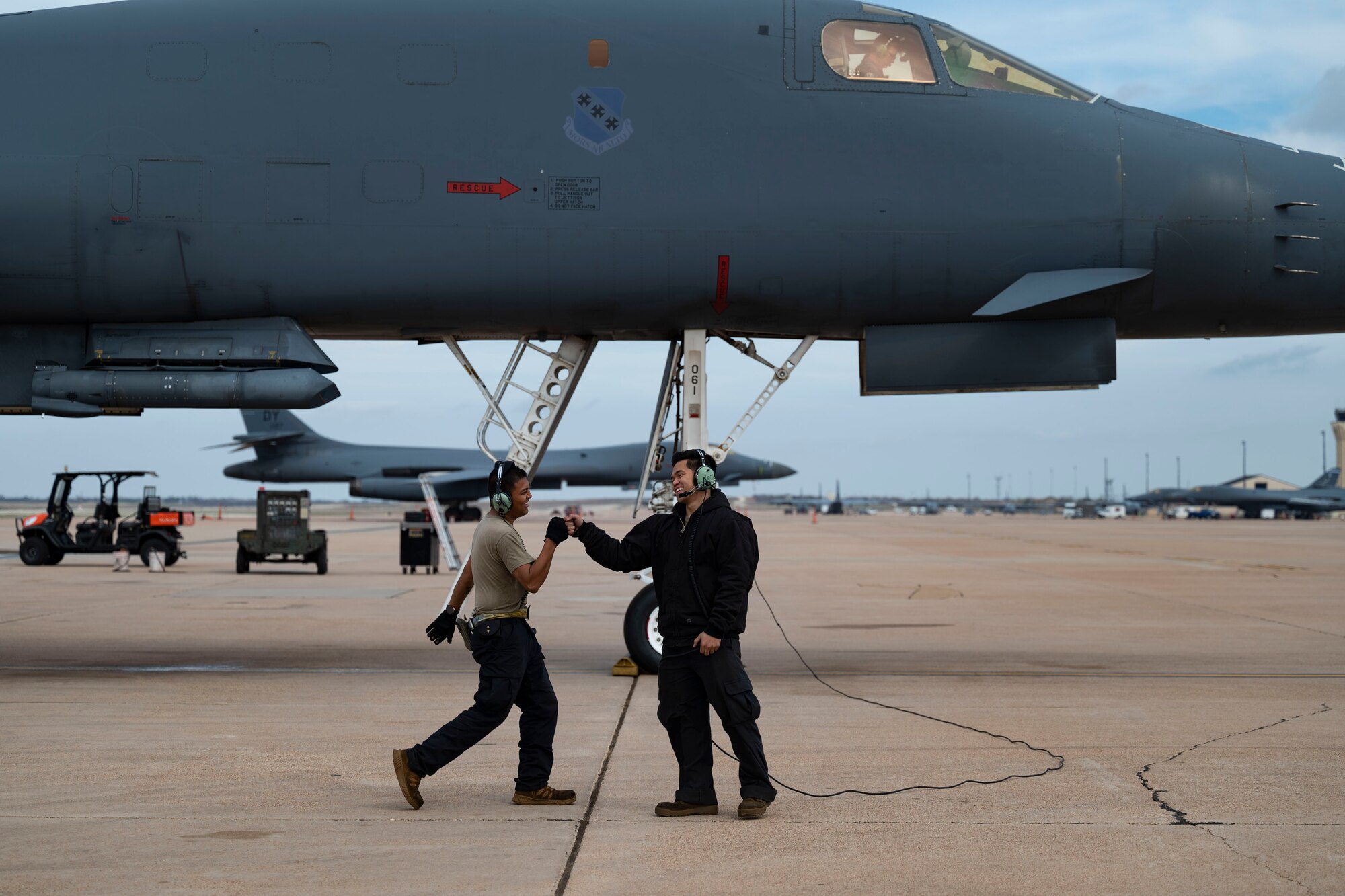 Two 7th Maintenance Group crew chiefs fistbump while conducting pre-flight maintenance checks on a B-1B Lancer at Dyess Air Force Base, Texas, March 22, 2023. In preparation for possible inclement weather, Dyess Airmen rapidly prepared over a dozen aircraft to relocate, successfully demonstrating America’s Lift and Strike Base’s ability to achieve dynamic force employment while using agile combat employment. The B-1s were temporarily relocated to Holloman Air Force Base, New Mexico, while the C-130s flew to several airfields throughout the United States. (U.S. Air Force photo by Airman Emma Anderson)
