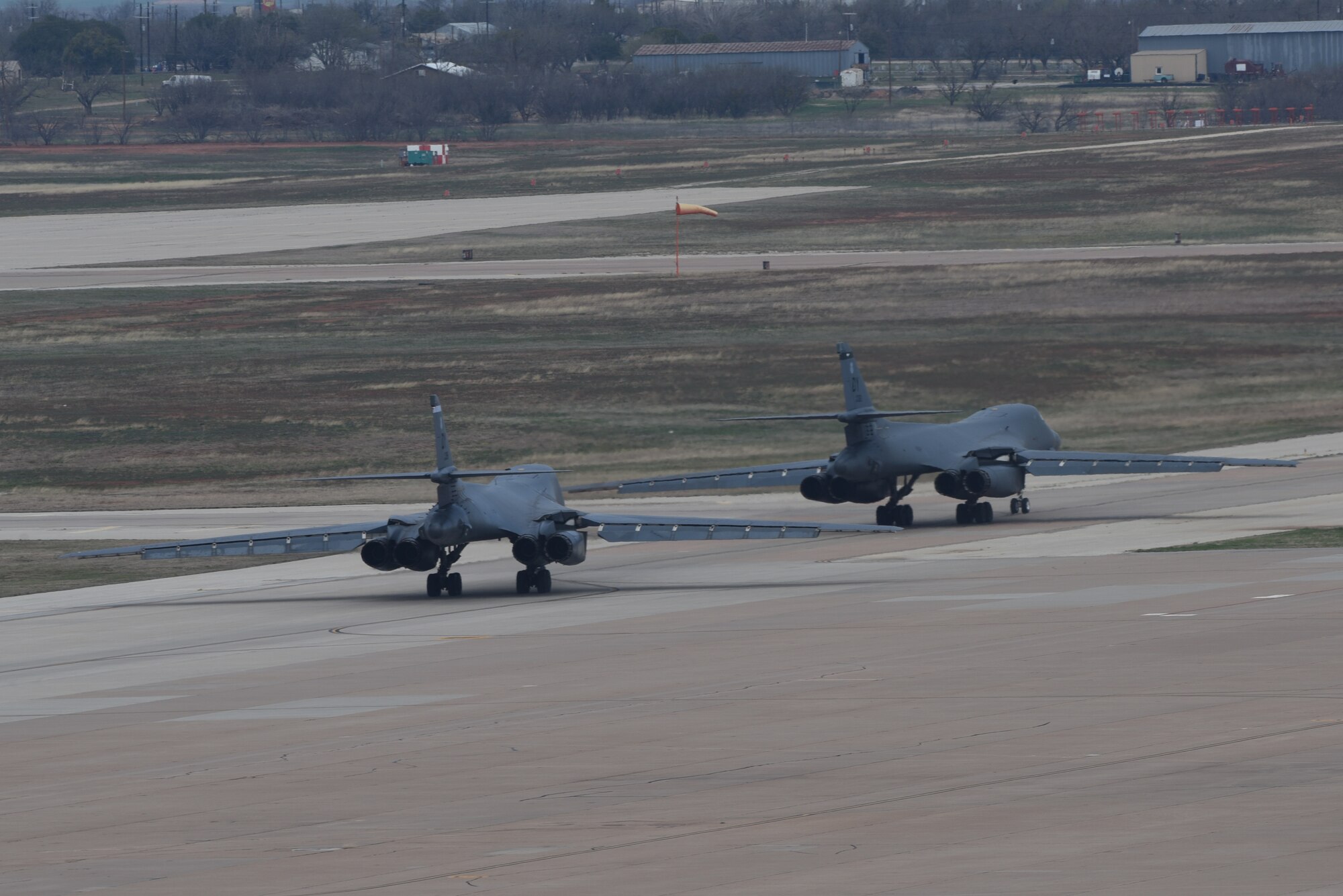 Two B-1B Lancers taxi on the runway at Dyess Air Force Base, Texas, March 22, 2023. In preparation for possible inclement weather, Dyess Airmen rapidly prepared over a dozen aircraft to relocate, successfully demonstrating America’s Lift and Strike Base’s ability to achieve dynamic force employment while using agile combat employment. The B-1s were temporarily relocated to Holloman Air Force Base, New Mexico, while the C-130s flew to several airfields throughout the United States. (U.S. Air Force photo by Senior Airman Sophia Robello)