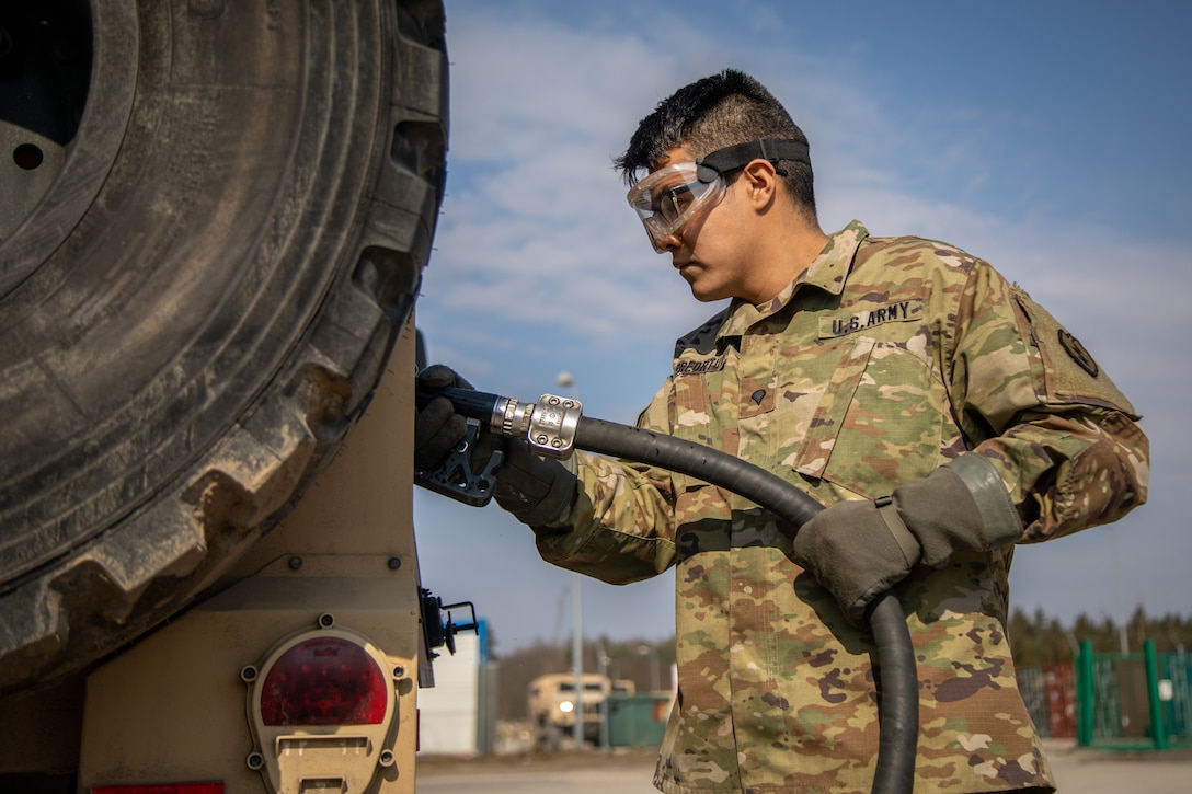 A soldier holds a hose while refueling a vehicle