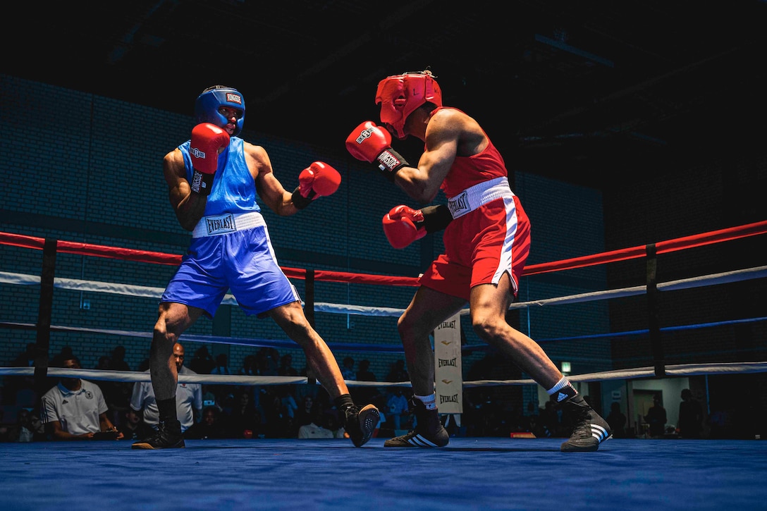 Two soldiers spar against each other in a boxing ring.