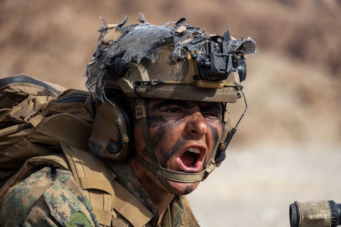 Close-up of a Marine wearing face paint, shouting commands.