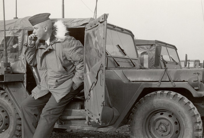 A man stands outside a military jeep.
