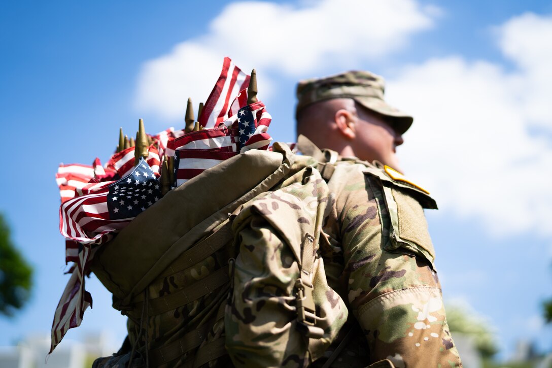 Service members place American flags at headstones in Arlington National Cemetery, Arlington, Va., May 27, 2021.