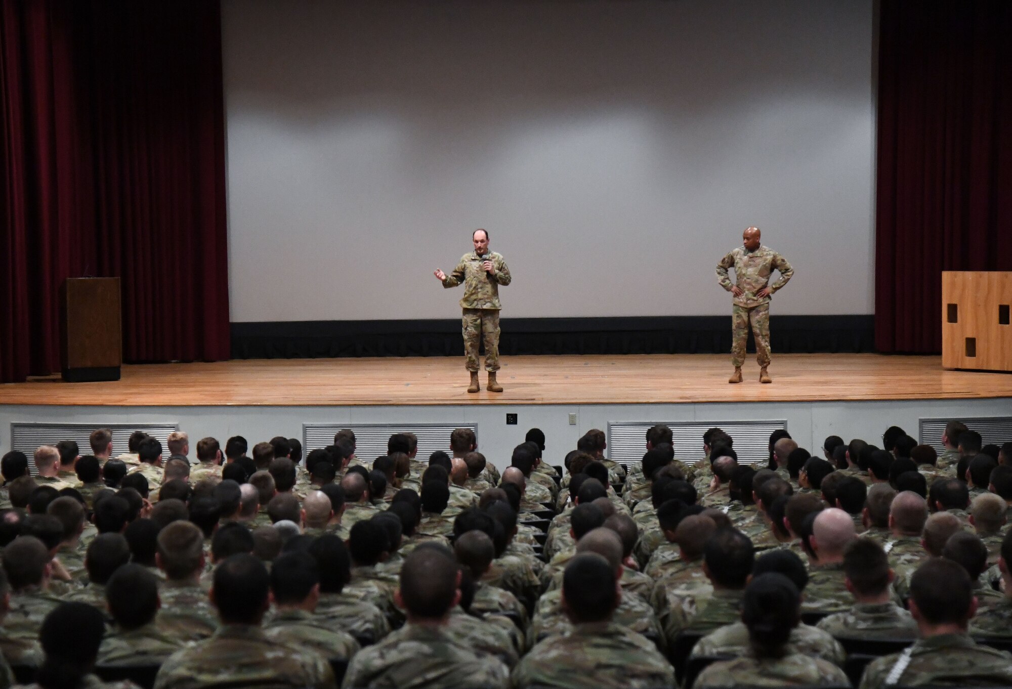 U.S. Air Force Lt. Gen. Kevin Kennedy, 16th Air Force commander, delivers remarks to cyber students as Chief Master Sgt. Keith Bruce, 16th AF command chief, stands by during an all call inside the Welch Theater at Keesler Air Force Base, Mississippi, March 22, 2023.