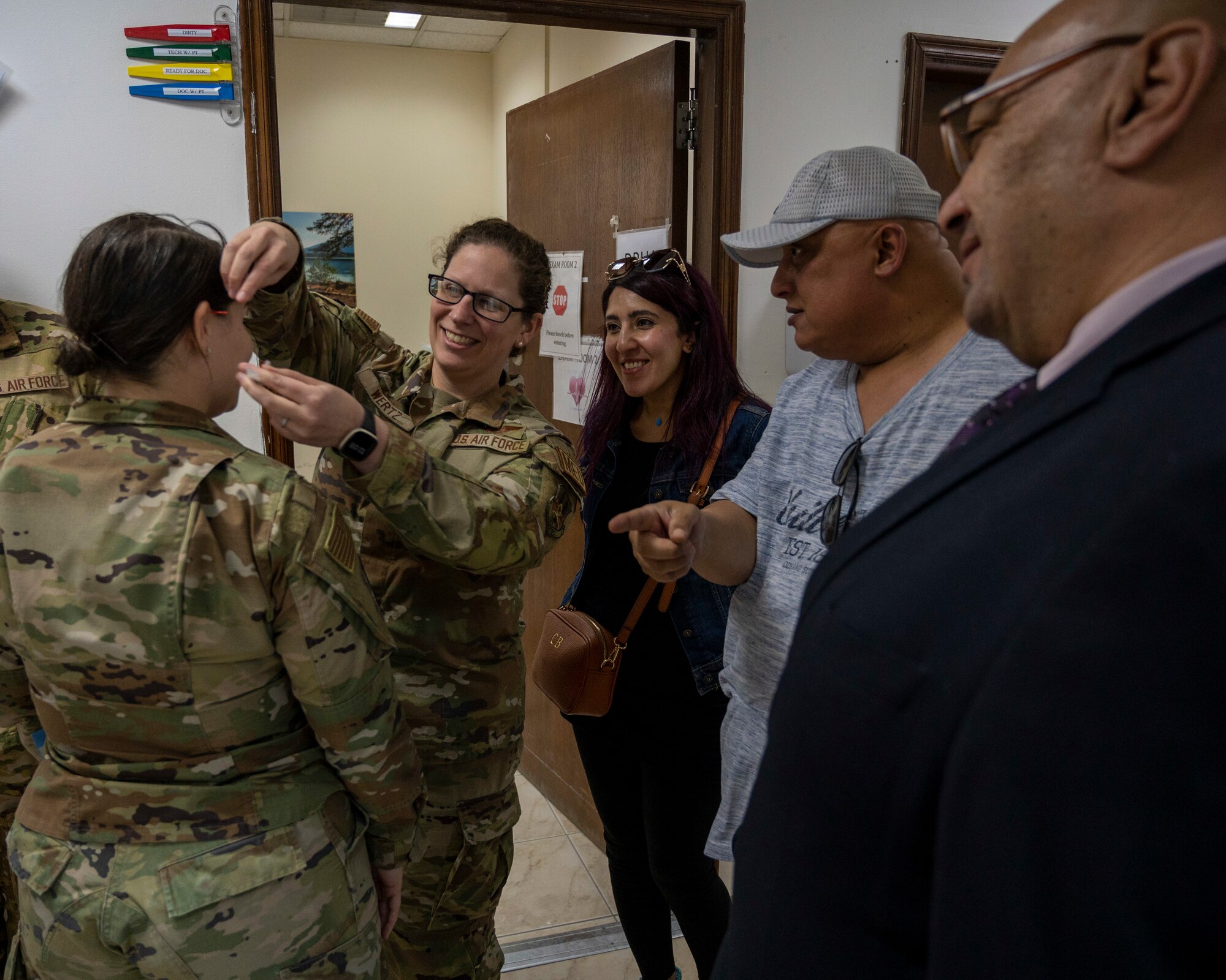 Kuwaiti Media watch as U.S. Air Force Major Maggie Wertz 386th Expeditionary Medical Squadron healthcare operations flight, puts an acupuncture needle into the ear of U.S. Air Force Captain Victoria Wright, 386th Air Expeditionary Wing public affairs chief, at Ali Al Salem Air Base, Kuwait, March 21, 2023.