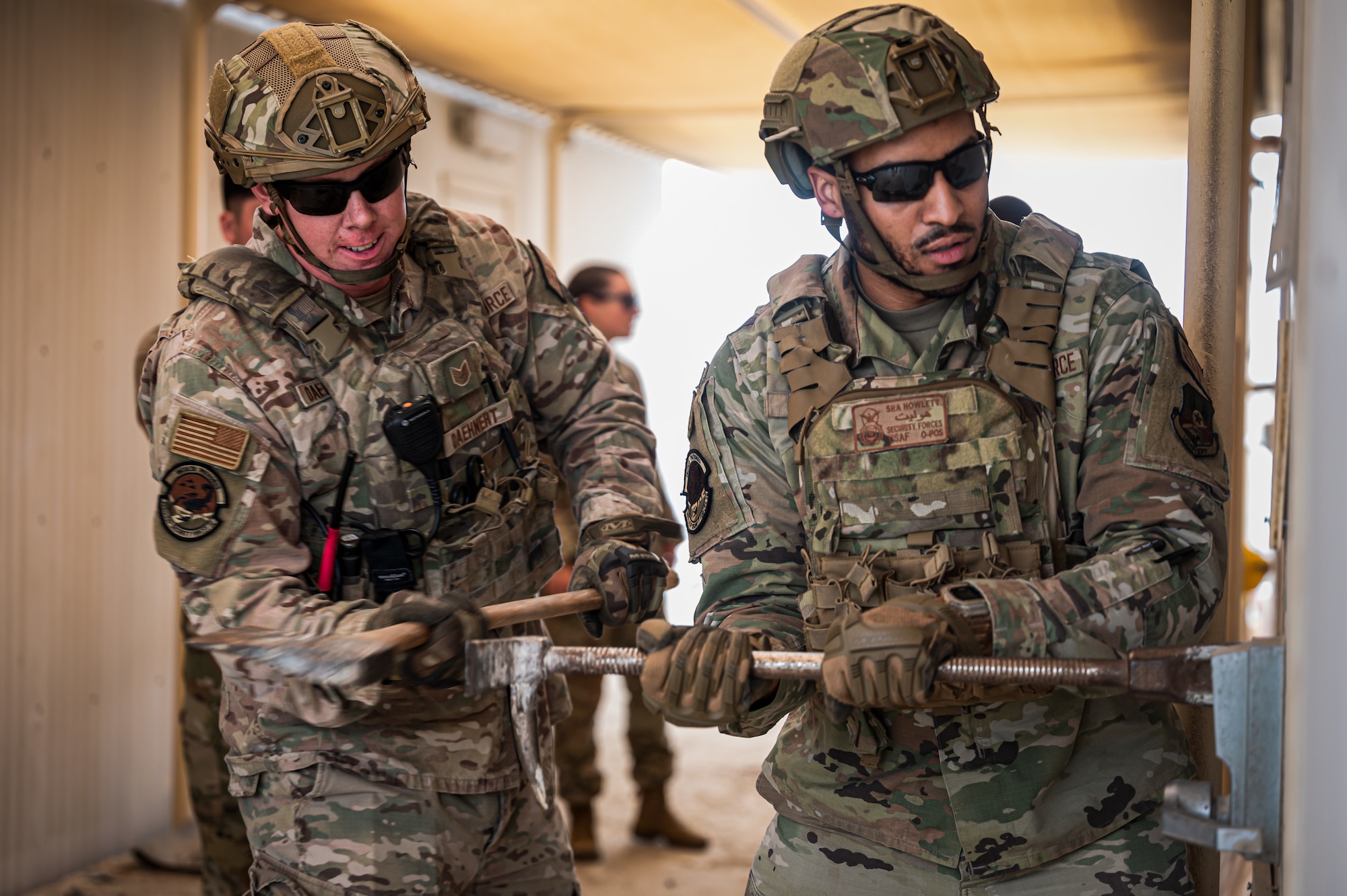 U.S. Air Force Tech. Sgt. Michael Daehneart (left) and Senior Airman Marrio Howlett, 380th Expeditionary Security Forces Squadron members, practice their forcible entry procedures in a building that is slated for demolition at Al Dhafra Air Base, United Arab Emirates, March 19, 2023. Defenders trained alongside 380th Expeditionary Civil Engineer Squadron firefighters and EOD Airmen to complete the realistic on-the-job training, using the unique opportunity of a location to train on to the full capacity. (U.S. Air Force photo by Staff Sgt. Sabatino DiMascio)