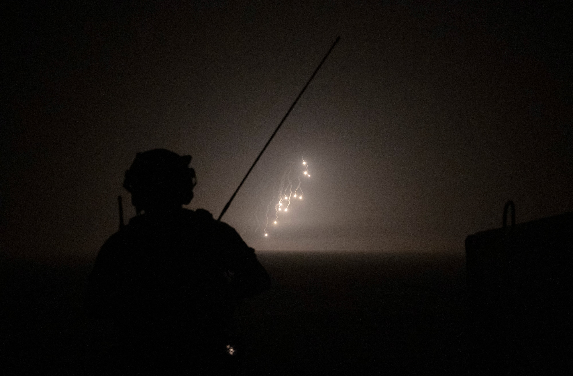 A U.S. Air Force tactical air control party Airman from the 82nd Expeditionary Air Support Operation Squadron watches as illumination rounds light up the sky at Udairi Range, Kuwait, March 14, 2023.