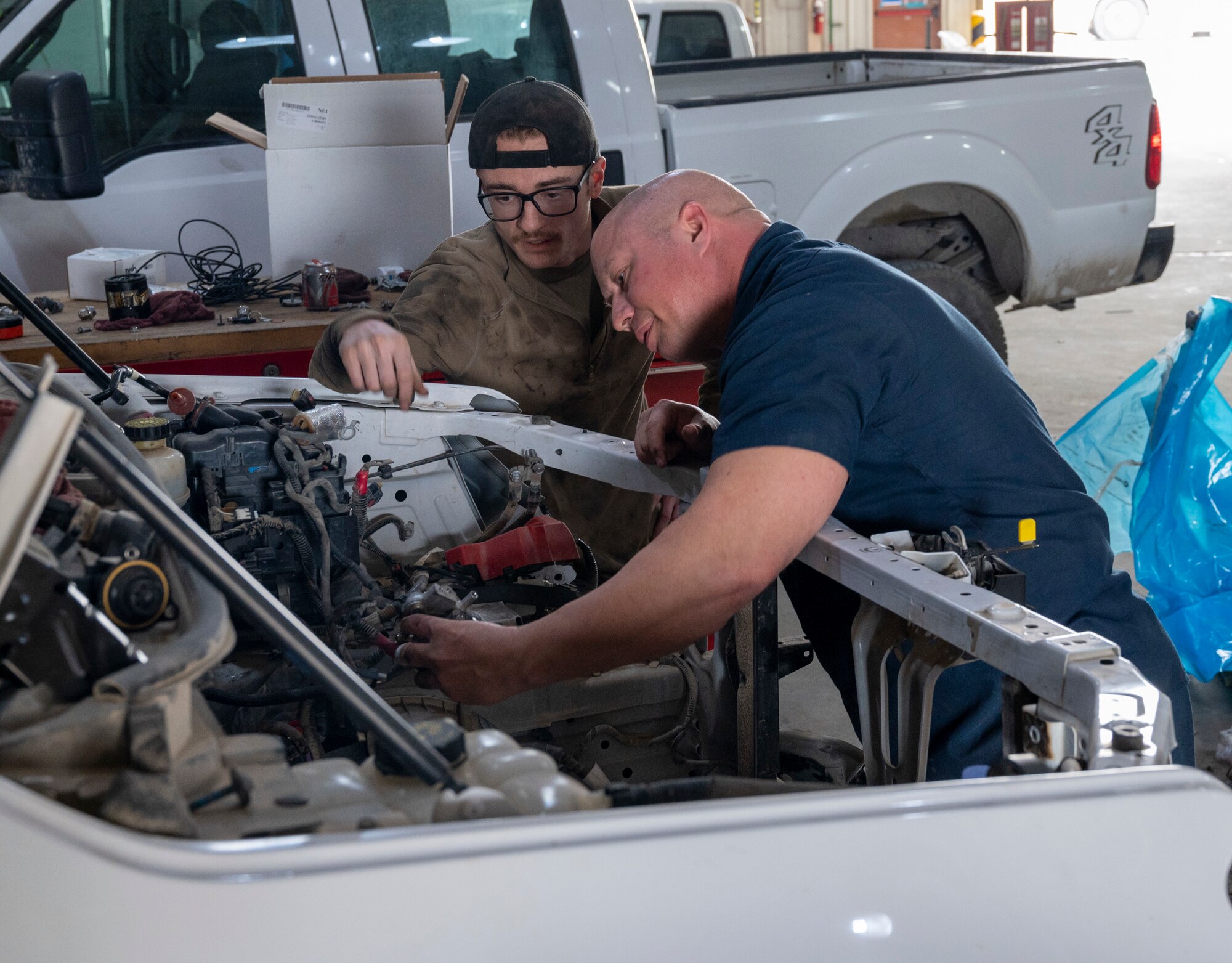 U.S. Air Force Airman 1st Class William Glendenning, Left, and U.S. Air Force Tech Sgt. Jeffery Burch, Right, 386th Expeditionary Logistics Readiness Squadron vehicle management specialists, inspect an engine bay at Ali Al Salem Air Base, Kuwait, March 8, 2023.