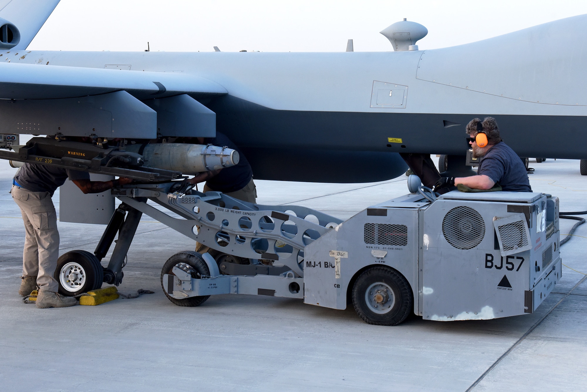 Amentum Contractors with the 62nd Expeditionary Attack Squadron at Al Dhafra Air Base, United Arab Emirates, attach a dummy munition to a U.S. MQ-9 Reaper during the Operation Agile Spartan 4 exercise, March 10, 2023. The exercise validated new Agile Combat Employment capabilities for Al Dhafra AB by simulating the establishment and use of mock cluster bases, which then reported back to the Wing Operations Center. (U.S. Air Force photo by Tech. Sgt. Chris Jacobs/released)