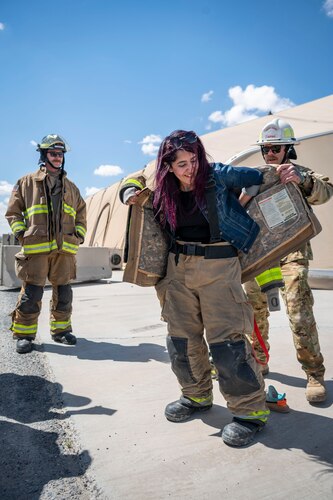 U.S. Air Force Master Sgt. Joseph Masiello, the 386th Expeditionary Civil Engineer Squadron assistant chief of operations, helps Ms. Mai Alsoukari, a Kuwaiti newspaper journalist, put on firefighter gear during Media Day at Ali Al Salem Air Base, Kuwait, March 21, 2023.