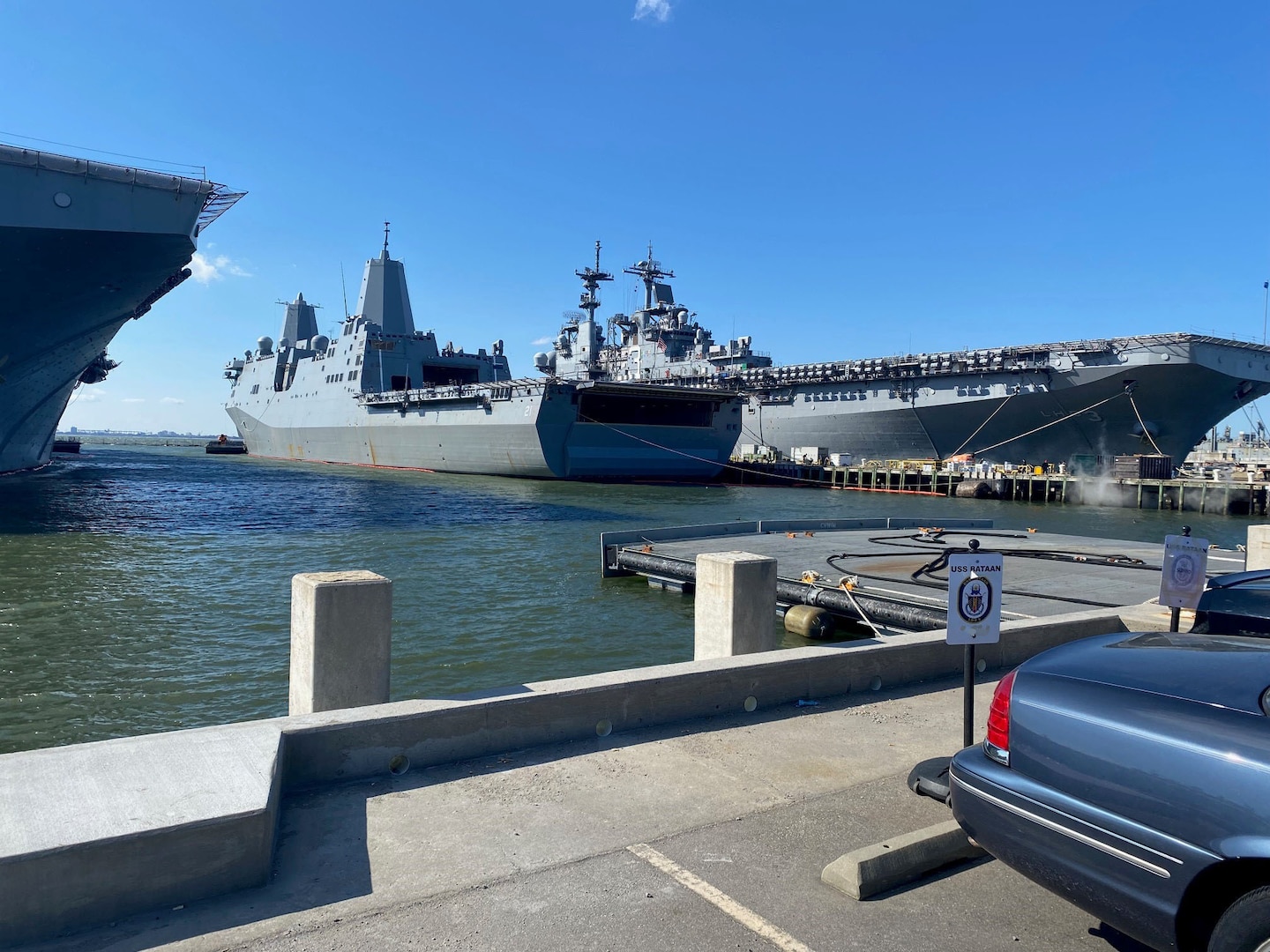 A large grey Navy ship docked on a Navy base.