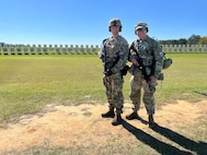 Two men in U.S. Army uniforms on outdoor rifle range.