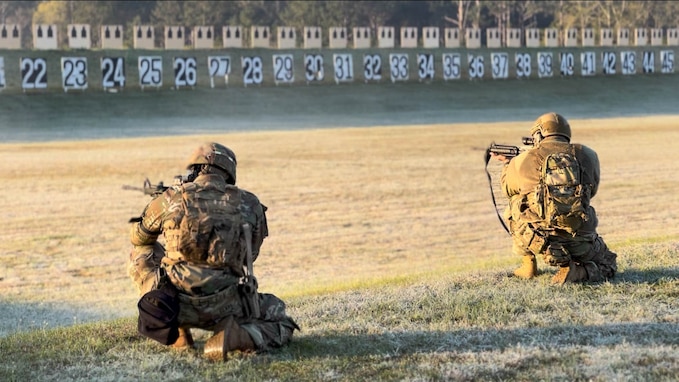 Multiple men in U.S. Army uniforms on outdoor rifle range.