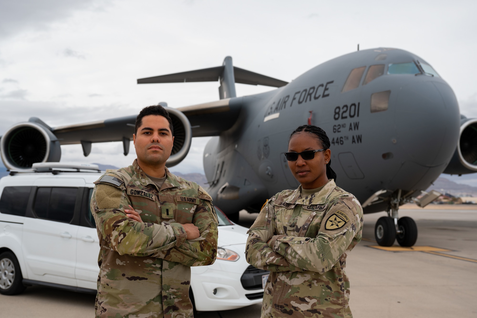 United States Army 1st Lt. Erickson Gonzalez, left, and Sgt. Monique Easy, Joint Communications Support Element, pose in front of the van and C-17 used in the Command and Control Element during Black Flag 23-1 operations at Nellis Air Force Base, Nevada, Feb. 23, 2023. This operation was accomplished by the combined effort between the C2 teams both on the ground and on the C-17 as they shared real time data to facilitate live operations. (U.S. Air Force photo by Airman 1st Class Josey Blades)