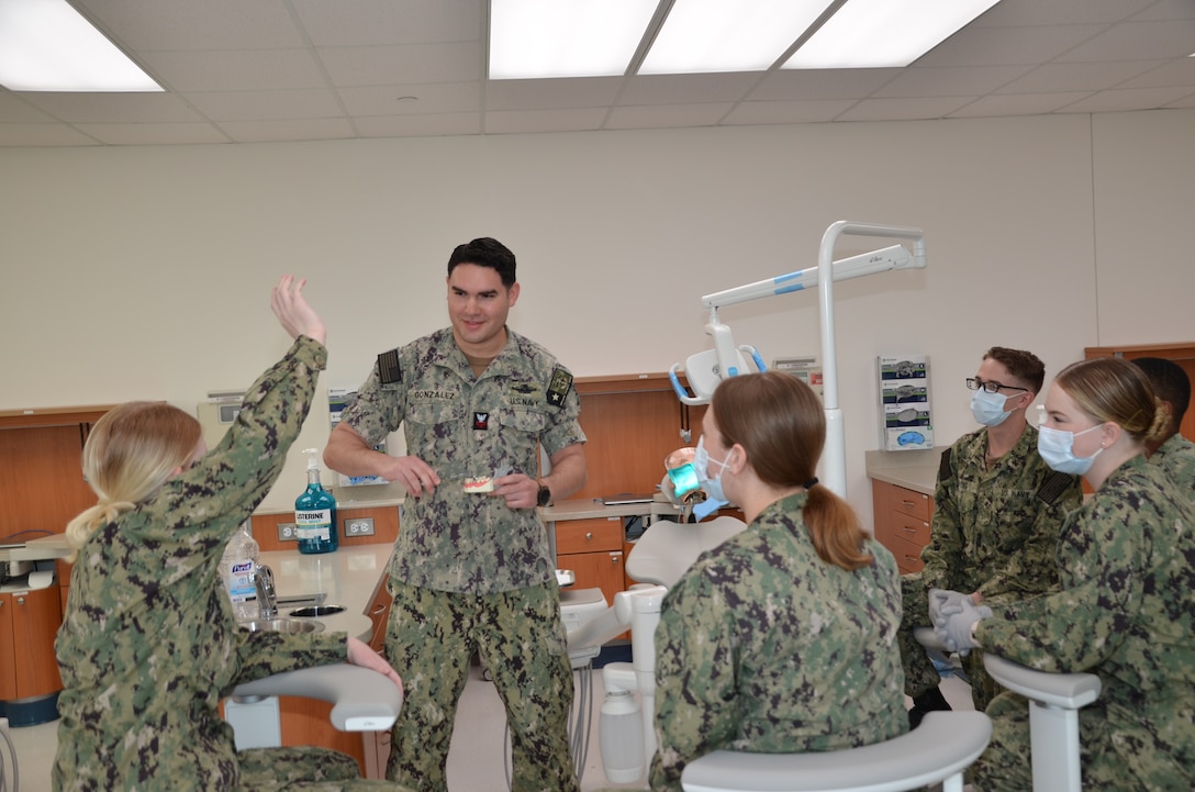 Petty Officer 1st Class Caleb Gonzalez reviews a lesson with students in the Navy dental assistant program at the Medical Education and Training Campus on Joint Base San Antonio-Fort Sam Houston, Texas. Gonzalez, an instructor in the program, will realize a childhood dream when he begins dental school this summer.