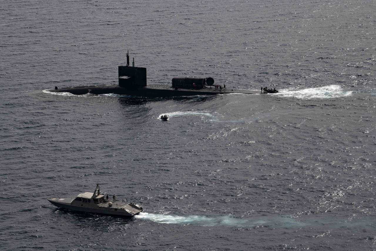 A boat, a submarine and a ship sail next to each other.