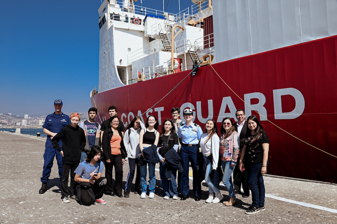U.S. Coast Guard Chief Warrant Officer John Skinner and Lt. Lauren Kowalski, U.S. Coast Guard Cutter Polar Star (WAGB 10) crewmembers, pose with youth from the Instituto Chileno Norteamericano de Cultura Valparaíso, on the pier next to the Polar Star in Valparaiso, Chile, March 21, 2023. The youth came aboard for tours to talk with the crew about the recent Operation Deep Freeze 2023 mission and learn about ice breaking operations. (U.S. Coast Guard photo by Senior Chief Petty Officer Charly Tautfest)