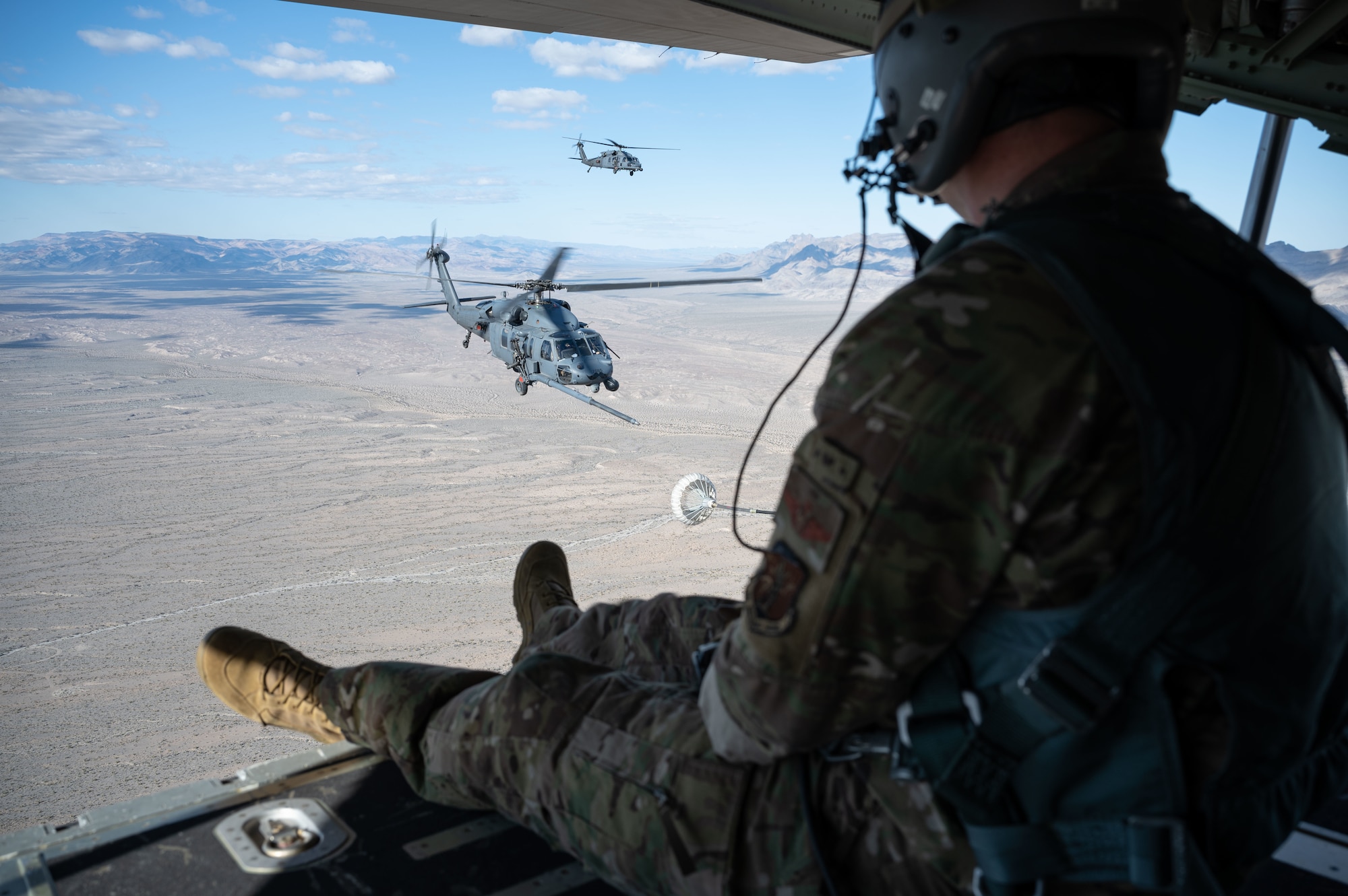 U.S. Air Force Master Sgt. David Williams a loadmaster assigned to the 102nd Rescue Squadron, New York Air National Guard, watches as two HH-60G Pave Hawks engage in refueling operations during Red Flag-Nellis 23-2 at Nellis Air Force Base, Nevada, March 16, 2023.