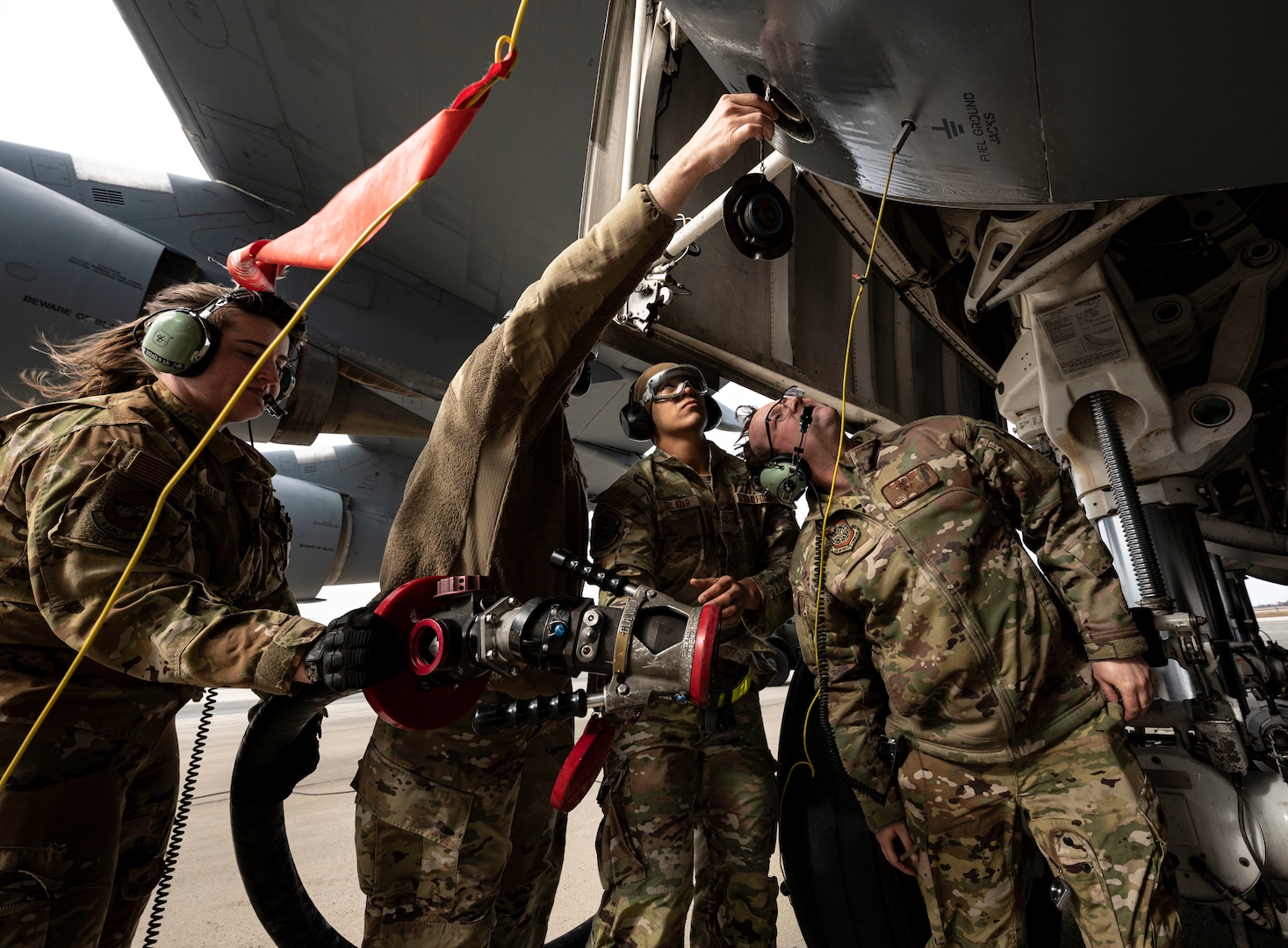 Airmen from the 436th Logistics Readiness Squadron and 9th Airlift Squadron discuss fuel hose attachment procedures on a C-5M Super Galaxy during a wet wing defuel at Dover Air Force Base, Delaware, March 1, 2023. Aircrew with the 9th AS test out new capabilities that allow the C-5 to act as a mobile fuel station and deposit fuel from the aircraft fuel tanks, into tankers standing by. (U.S. Air Force photo by Staff Sgt. Marco A. Gomez)