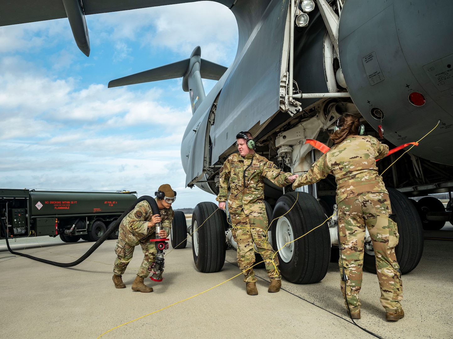 From the left, Airman 1st Class Casey Salazar 436th Logistics Readiness Squadron fuels distribution operator, Senior Airman Beau Dormer, 9th Airlift Squadron loadmaster, and Staff Sgt. Amelia Bradfield, 9th AS loadmaster, prepare to attach a fuel hose from an R-11 Refueler onto a C-5M Super Galaxy during a wet wing defuel at Dover Air Force Base, Delaware, March 1, 2023. Aircrew with the 9th AS test out new capabilities that allow the C-5 to act as a mobile fuel station and deposit fuel from the aircraft fuel tanks, into tankers standing by. (U.S. Air Force photo by Staff Sgt. Marco A. Gomez)