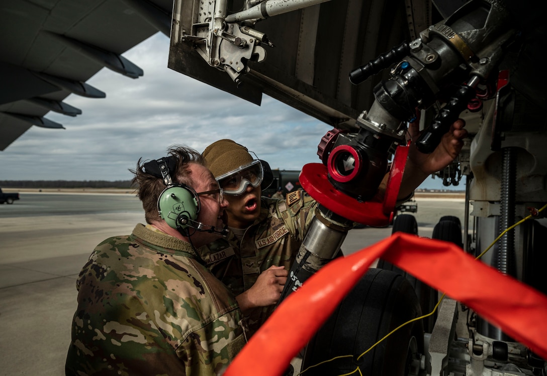 Staff Sgt. Kyle Hewitt, left, 9th Airlift Squadron flight engineer, and Airman 1st Class Casey Salazar, right, 436th Logistics Readiness Squadron fuels distribution operator, secure a fuel hose from an R-11 Refueler onto a C-5M Super Galaxy during a wet wing defuel at Dover Air Force Base, Delaware, March 1, 2023. Aircrew with the 9th AS test out new capabilities that allow the C-5 to act as a mobile fuel station and deposit fuel from the aircraft fuel tanks, into tankers standing by. (U.S. Air Force photo by Staff Sgt. Marco A. Gomez)