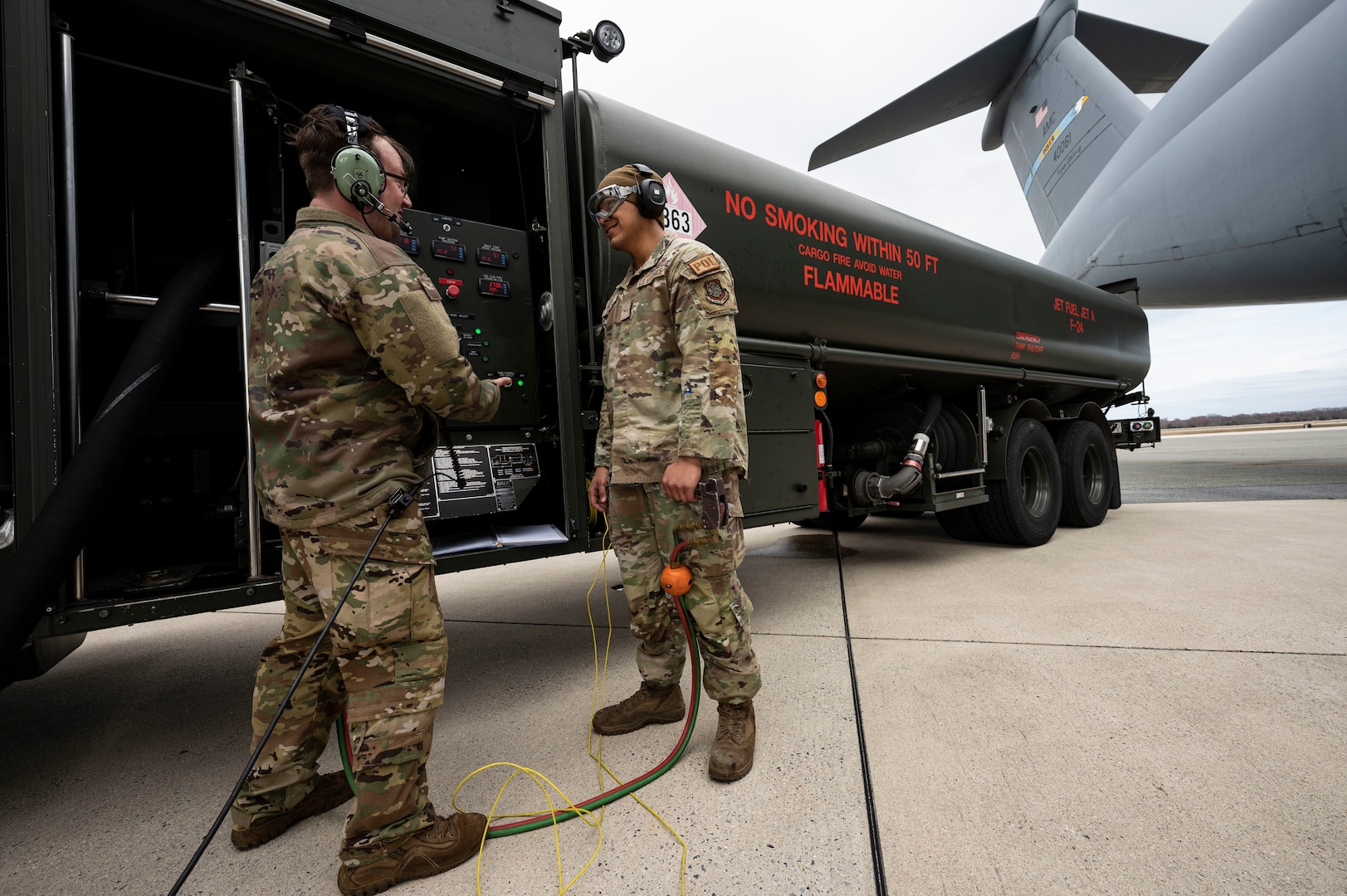 Staff Sgt. Kyle Hewitt, left, 9th Airlift Squadron flight engineer, and Airman 1st Class Casey Salazar, right, 436th Logistics Readiness Squadron fuels distribution operator, discuss defuel procedures on a C-5M Super Galaxy during a wet wing defuel at Dover Air Force Base, Delaware, March 1, 2023. Aircrew with the 9th AS test out new capabilities that allow the C-5 to act as a mobile fuel station and deposit fuel from the aircraft fuel tanks, into tankers standing by. (U.S. Air Force photo by Staff Sgt. Marco A. Gomez)