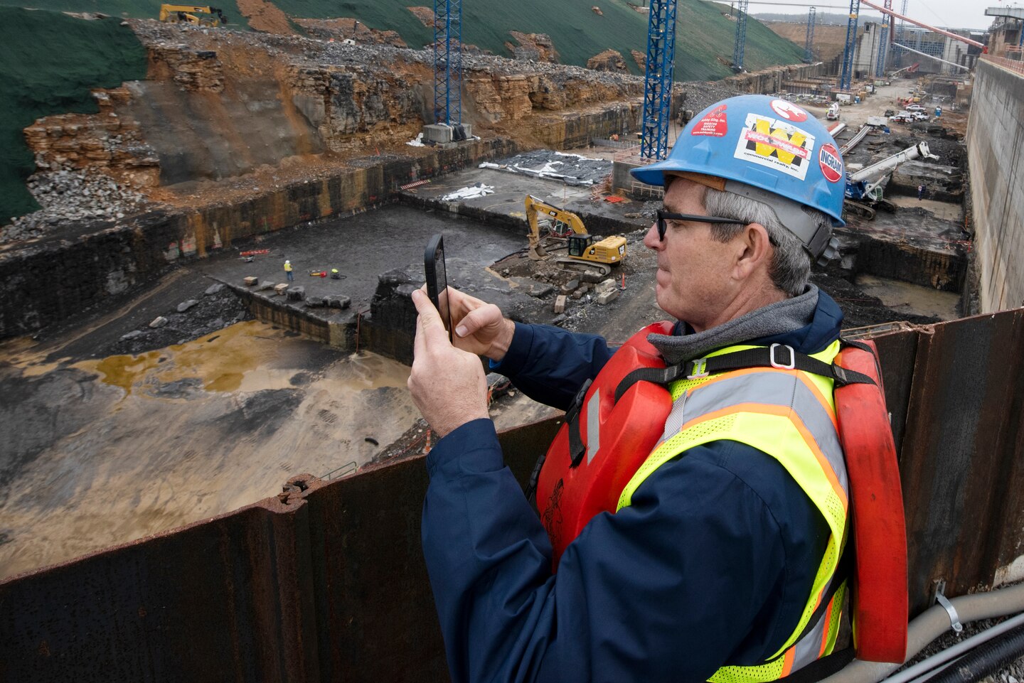 Jason Adams, Inland Marine Service chief executive officer, takes photos with his phone of the Kentucky Lock Addition Project during a stakeholder tour to see ongoing construction of the downstream section of the lock chamber. The Nashville District engaged with stakeholders March 22, 2023, to provide an update on the important navigation project and to promote partnerships and communication. (USACE Photo by Lee Roberts)