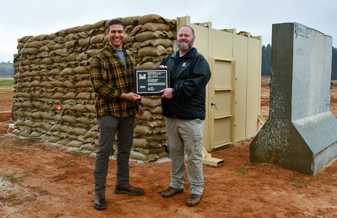 Greg Taylor, P.E., U.S. Army Corps of Engineers Transatlantic Middle East District chief of engineers (right), presents an Army Corps of Engineers Innovation Of the Year award plaque to Brian J. Blusius, Middle East District structural engineer and design team lead for U.S. Army Central’s Bunker Retrofit project (left), prior to the U.S. Army Engineer Research and Development Center’s Phase II Live-fire Experiment at Fort Polk, La., Mar. 10.