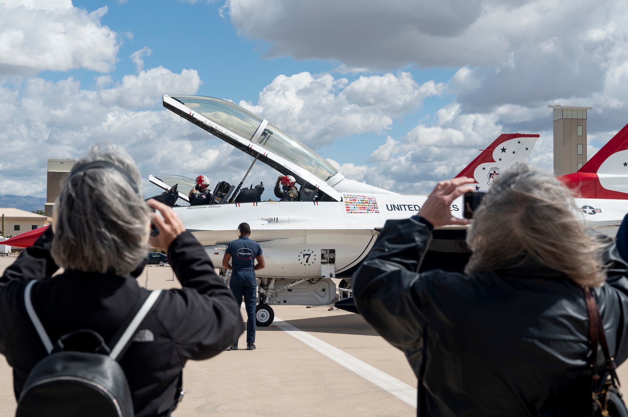 Photo of people in the foreground taking photos of people inside of a jet.