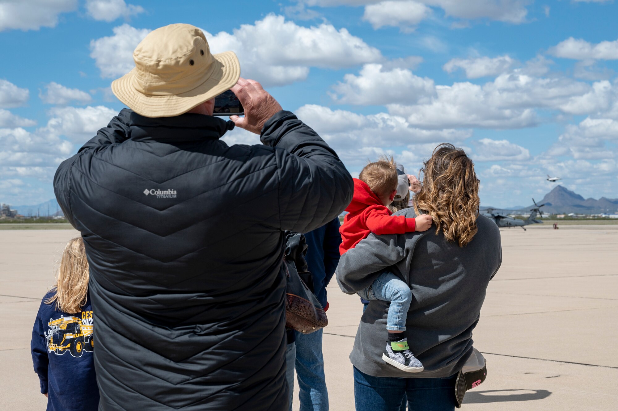 Photo of people and children watching an aircraft take off.