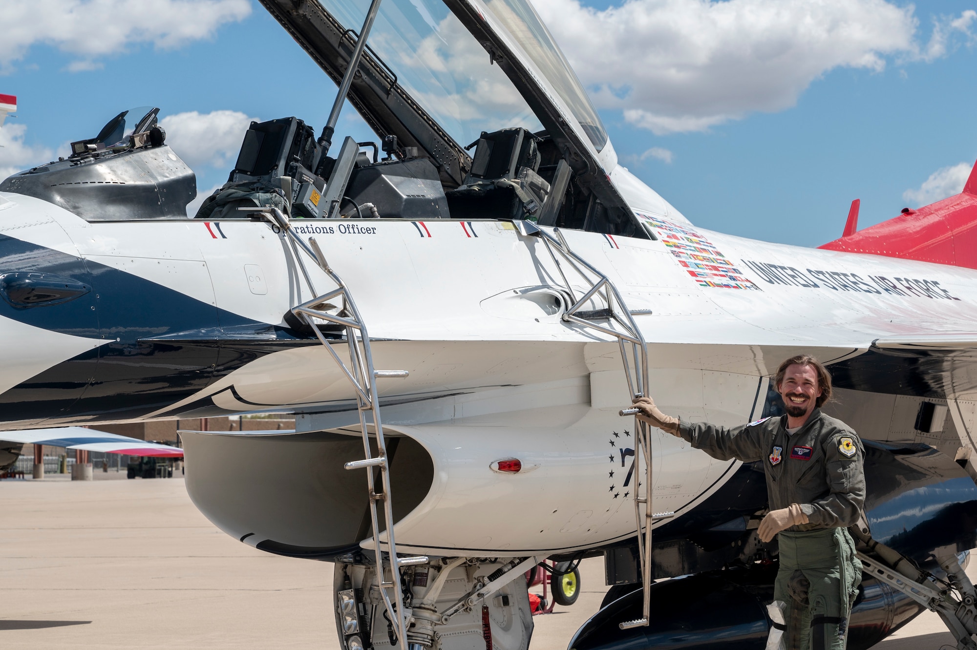 Photo of a smiling man next to a fighter jet.