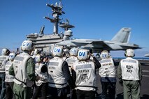 (March 23, 2023) Italian military and civilian leadership from Sicily and the U.S. Consulate in Naples watch an F/A-18E Super Hornet aircraft, attached to Strike Fighter Squadron (VFA) 136, land on the flight deck of the Nimitz-class aircraft carrier USS George H.W. Bush (CVN 77), March 23, 2023. Carrier Air Wing (CVW) 7 is the offensive air and strike component of Carrier Strike Group (CSG) 10 and the George H.W. Bush CSG. The squadrons of CVW-7 are VFA-143, VFA-103, VFA-86, VFA-136, Carrier Airborne Early Warning Squadron (VAW) 121, Electronic Attack Squadron (VAQ) 140, Helicopter Sea Combat Squadron (HSC) 5, and Helicopter Maritime Strike Squadron (HSM) 46. The George H.W. Bush CSG is on a scheduled deployment in the U.S. Naval Forces Europe area of operations, employed by U.S. Sixth Fleet to defend U.S., allied and partner interests.
