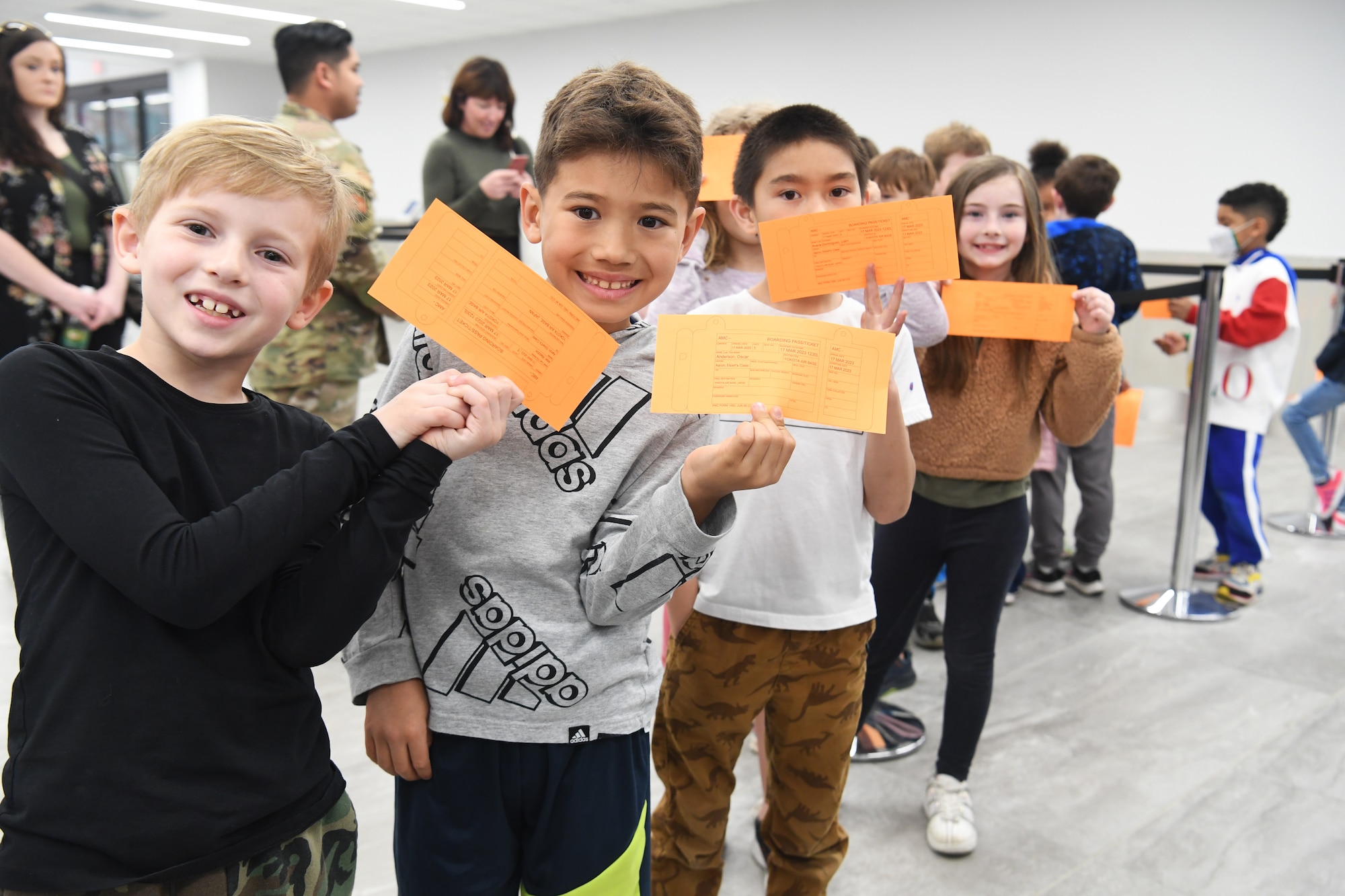 Students from Yokota West Elementary School pose for a photo while visiting the Yokota Passenger Terminal at Yokota Air Base, Japan, March 17, 2023.The kindergarten and first-grade classes traveled to the terminal with their teachers and parent chaperones, where they were greeted by 730th Air Mobility Squadron passenger services members and issued customized boarding passes to simulate a typical Air Mobility Command trip. (U.S. Air Force photo by Tech. Sgt. Taylor A. Workman)