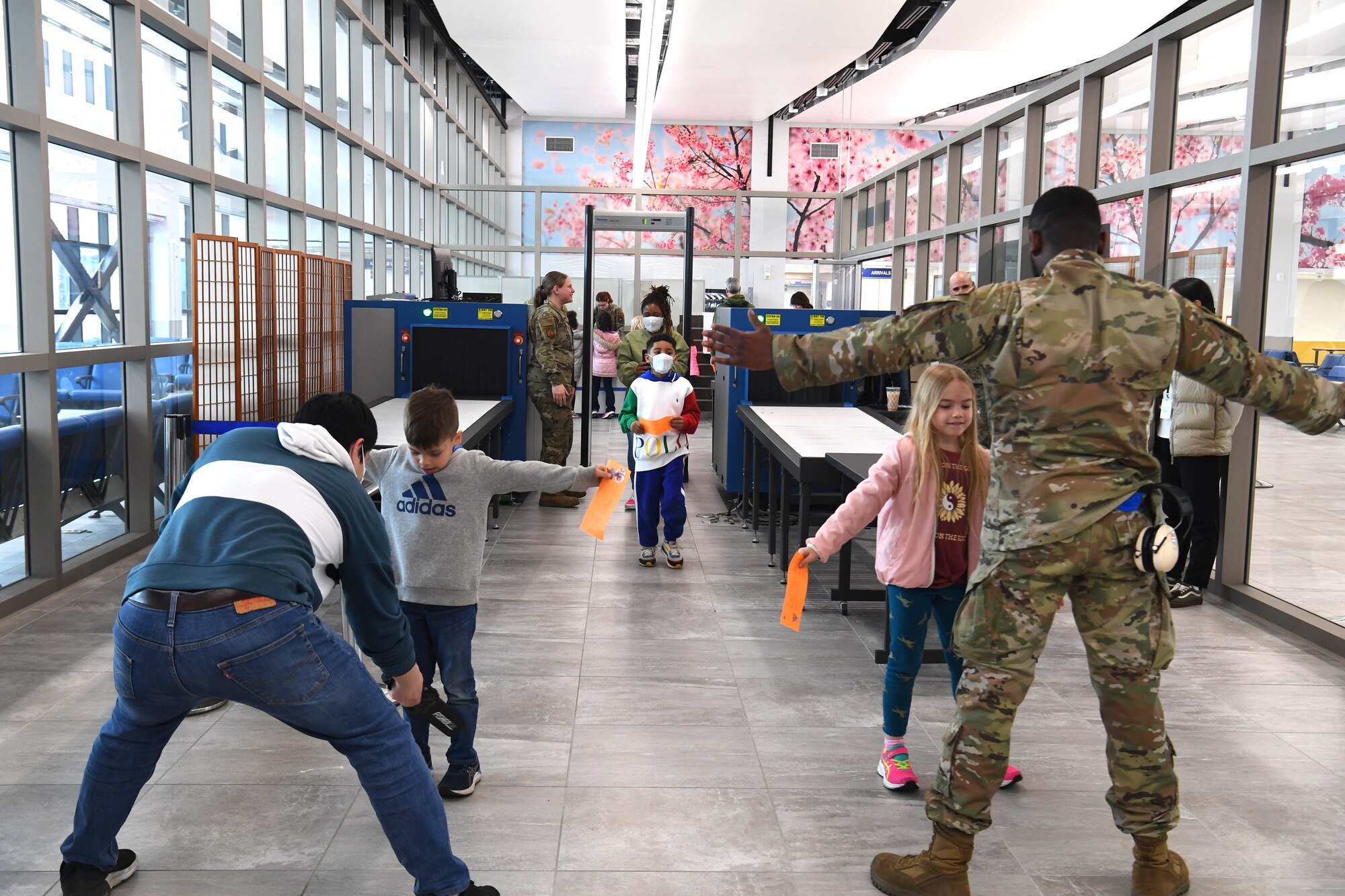 Yusuke Narai (left) and Airman 1st Class Timothy Jones, 730th Air Mobility Squadron passenger service agents, use hand-held metal detectors to simulate a security search of students visiting from Yokota West Elementary School at the Yokota Passenger Terminal, Yokota Air Base, Japan, March 17, 2023. The kids lined up and filed through the security inspection area to learn about how the 730th AMS ensures safe flights for all of their passengers. (U.S. Air Force photo by Tech. Sgt. Taylor A. Workman)