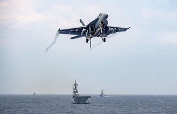 An F/A-18E Super Hornet prepares to land aboard USS Nimitz (CVN 68) as it steams ahead of JS Ise (DDH 182) and USS Decatur (DDG 73) and USS Wayne E. Meyer (DDG 108) in the Philippine Sea.
