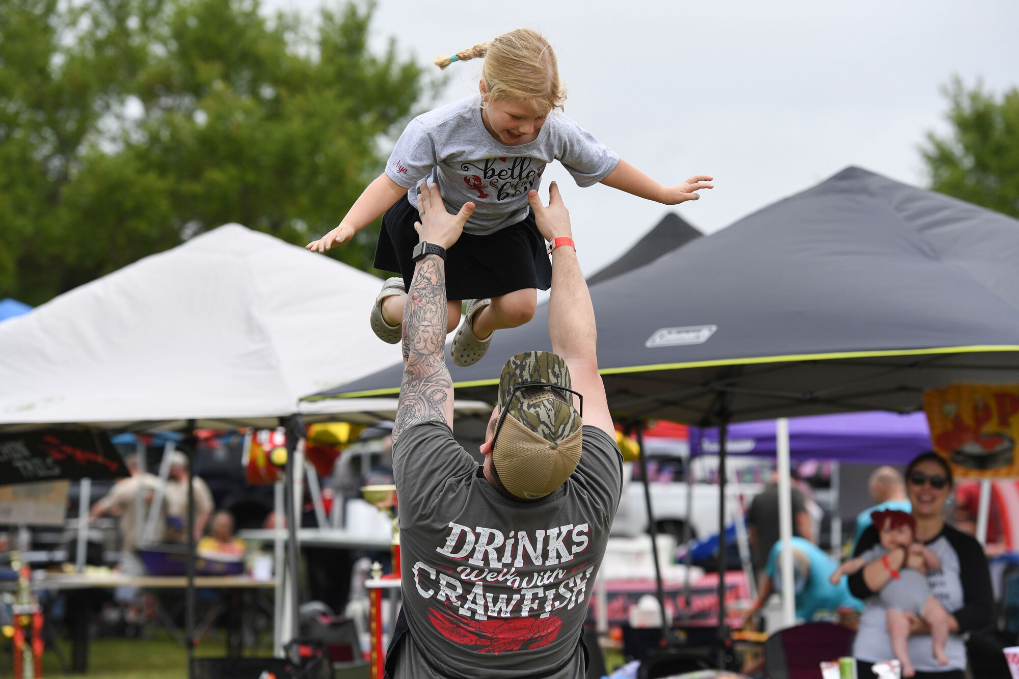 U.S. Air Force Maj. Ryan Anderson, 81st Healthcare Operations Squadron emergency room flight commander, Pinchn Tails team member, tosses his daughter, Arya, in the air during the 11th Annual Crawfish Cook-Off outside the Bay Breeze Event Center at Keesler Air Force Base, Mississippi, March 24, 2023.