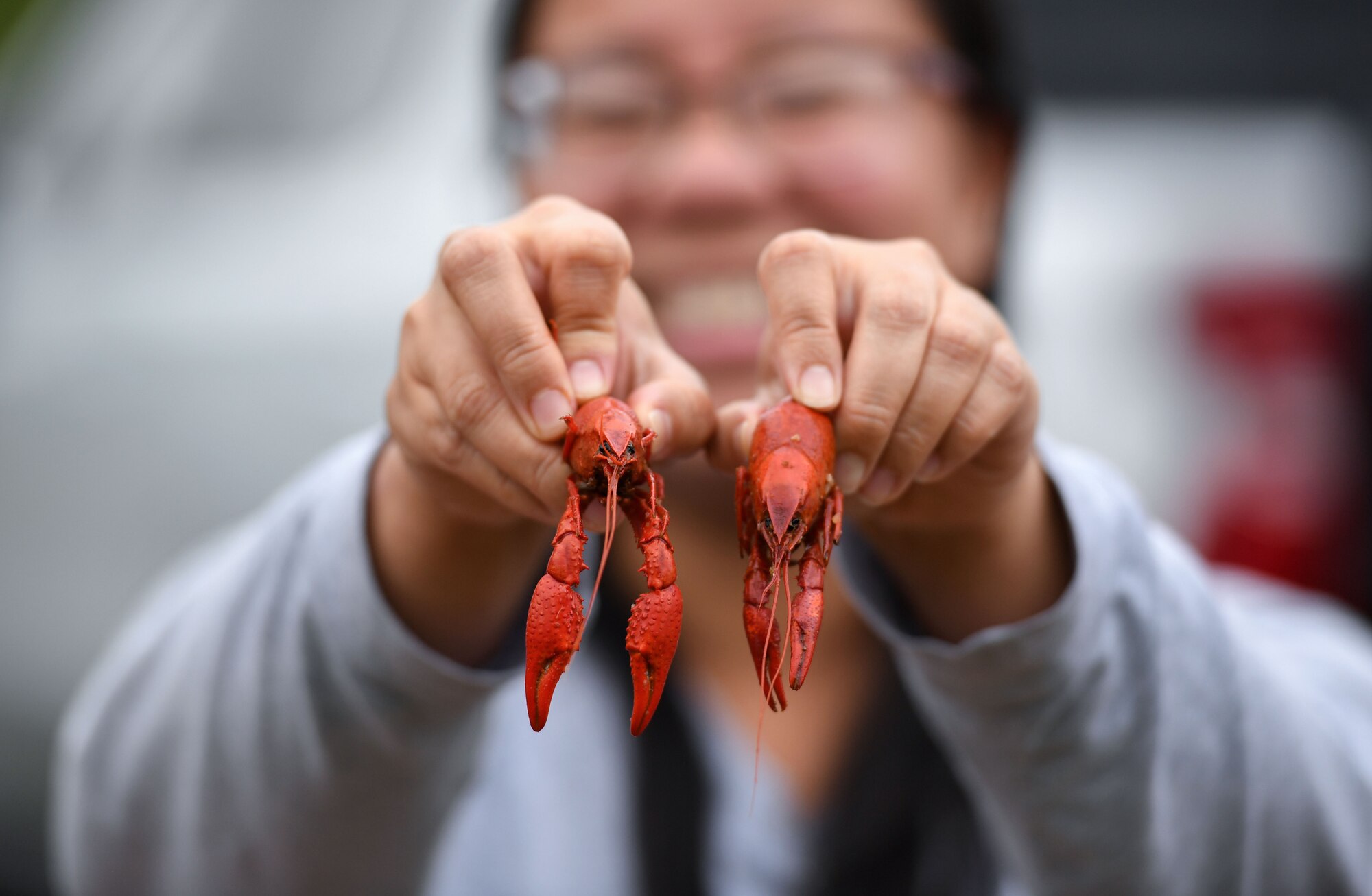 MyLien Nguyen, 81st Training Wing public affairs graphic illustrator, holds boiled crawfish in her hands during the 11th Annual Crawfish Cook-Off outside the Bay Breeze Event Center at Keesler Air Force Base, Mississippi, March 24, 2023.